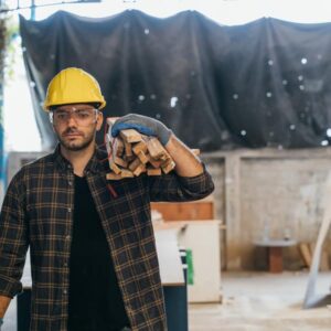Mann mit Helm beim tragen von Holz.