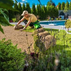 Mann beim Verlegen von Rollrasen