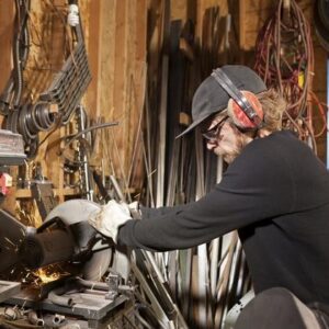 Mann mit Gehörschutz steht an einer Metallsäge